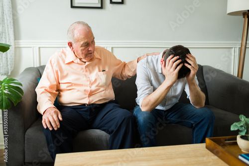 Crying young man talking with his elderly dad about sad things