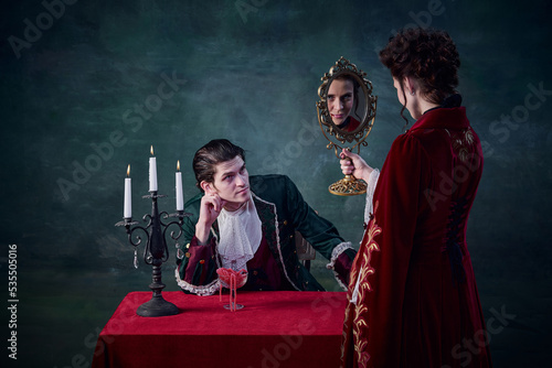 Portrait of woman in image of vampire looking in mirror to see her endless youth. Male looking at woman. Immortal family