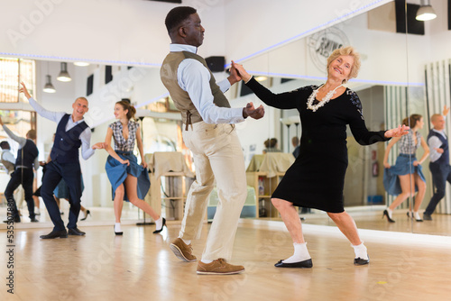 Man and elderly woman performing jazz dance in dancing room © caftor