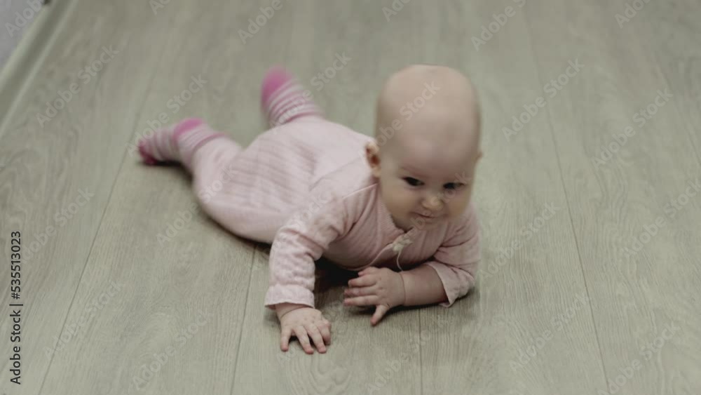 Little caucasian baby girl aged 6 months crawls on the floor in the house. Emotions on the face. Childish joy. Little caucasian baby girl aged 6 months crawls on the floor in the house. Emotions on the face. Childish joy.
