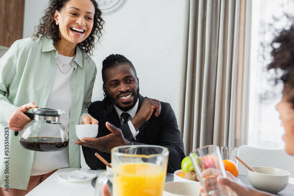 happy african american parents looking at curly preteen daughter during breakfast. happy african american parents looking at curly preteen daughter during breakfast.