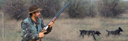 Hunter man in camouflage with a gun during the hunt in search of wild birds or game.