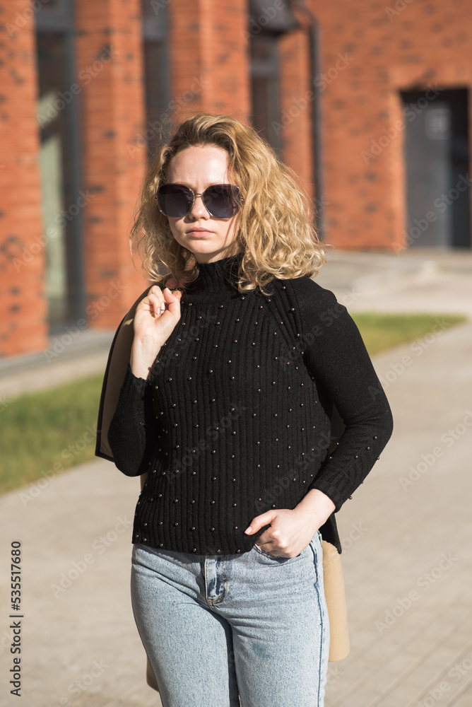 Portrait of a young Caucasian girl in a coat and sunglasses in the city on an autumn day. Portrait of a young Caucasian girl in a coat and sunglasses in the city on an autumn day.