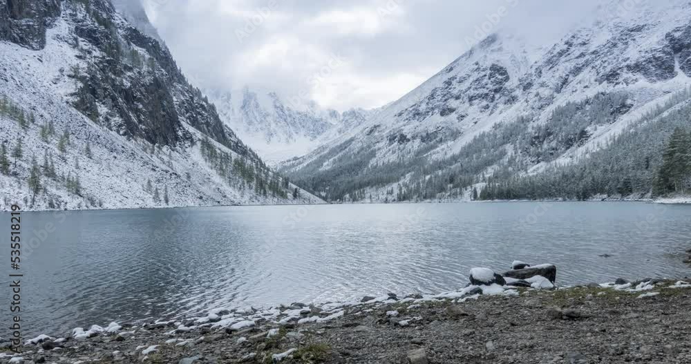 4K UHD snow mountain lake timelapse at the autumn time. Wild nature and rural mount valley. Green forest of pine trees and heavy clouds on sky. Motorised dolly slider movement 4K UHD snow mountain lake timelapse at the autumn time. Wild nature and rural mount valley. Green forest of pine trees and heavy clouds on sky. Motorised dolly slider movement