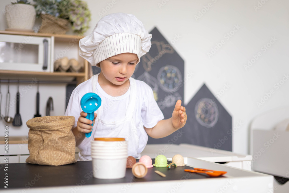 Cute male kid preparing toy food boiling vegetables on cooker at childish room kitchen Cute male kid preparing toy food boiling vegetables on cooker at childish room kitchen