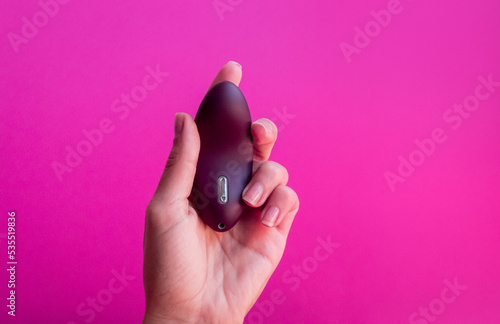 Sex toy for women, female hands holding a masturbator on the pink background.