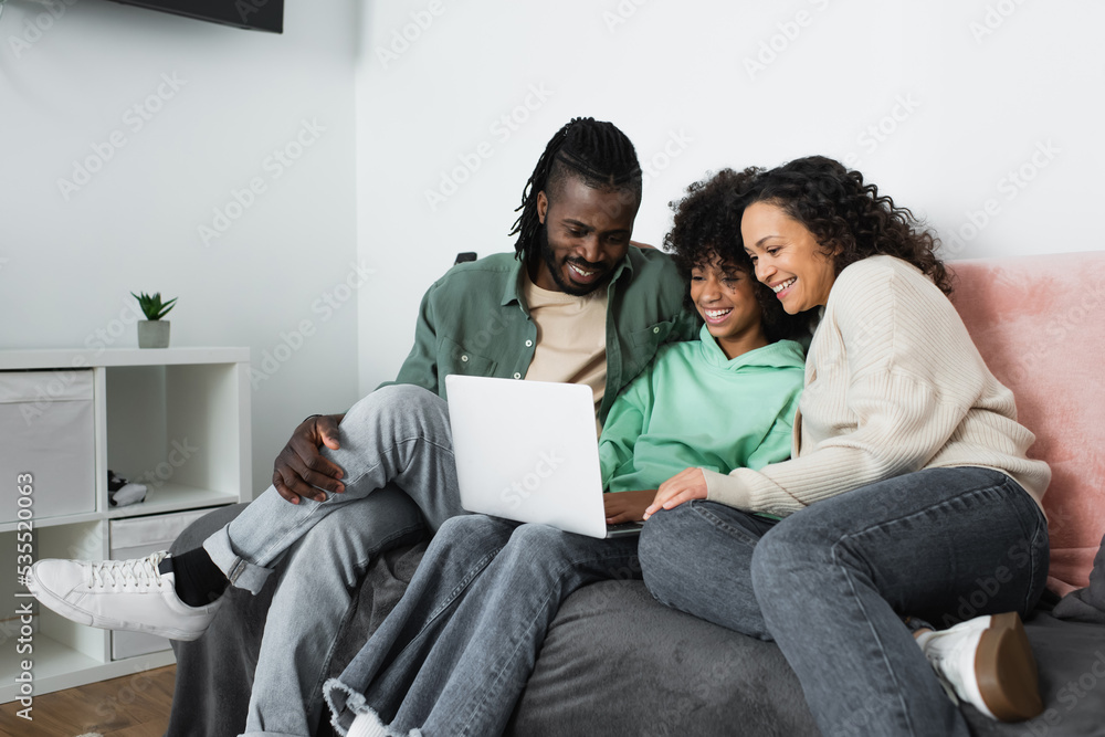 happy african american family watching comedy movie on laptop in living room. happy african american family watching comedy movie on laptop in living room.