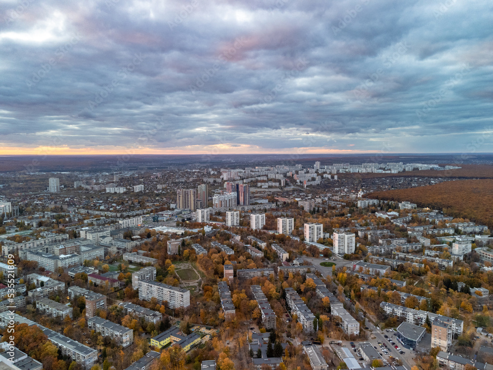Fototapeta premium Aerial autumn city sunset view with epic cloudscape. Pavlovo Pole residential district buildings in evening light. Kharkiv, Ukraine