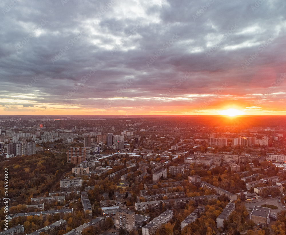 Aerial sunset city view, vivid autumn epic cloudscape. Botanical garden and Kharkiv city center. Residential district buildings in evening