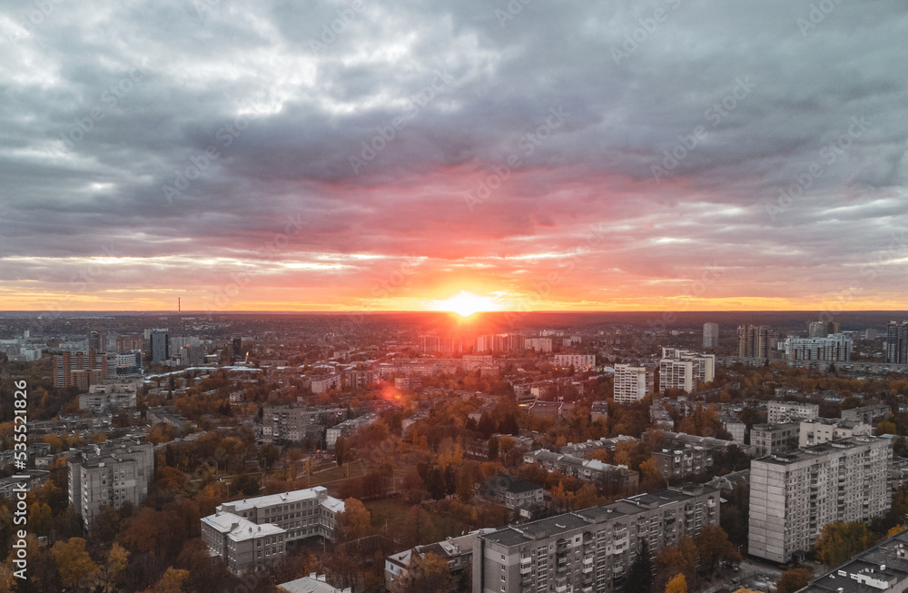 Aerial cityscape with shining sun, colorful sunset view with gray buildings. Kharkiv city center, Pavlove pole residential district in evening light