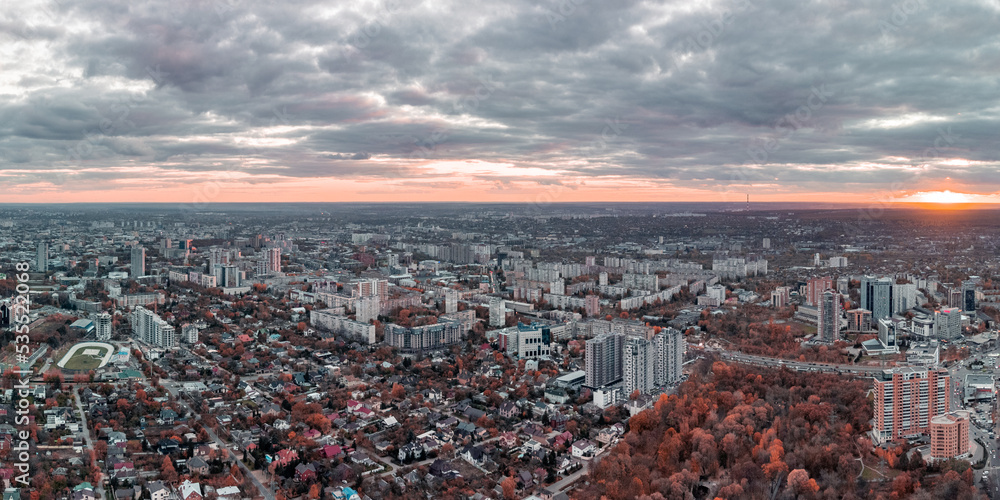 Aerial vivid red autumn city park sunset panorama view with epic cloudscape. Residential district buildings in evening light. Kharkiv, Ukraine