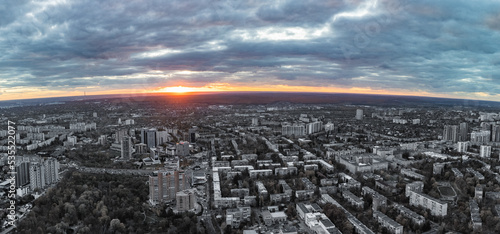Aerial colorless city and vivid sunset view with epic clouds. Botanical garden and Kharkiv city center. Residential district buildings in evening light