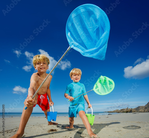 Two boys catcher of small critters on the ocean beach Fototapet