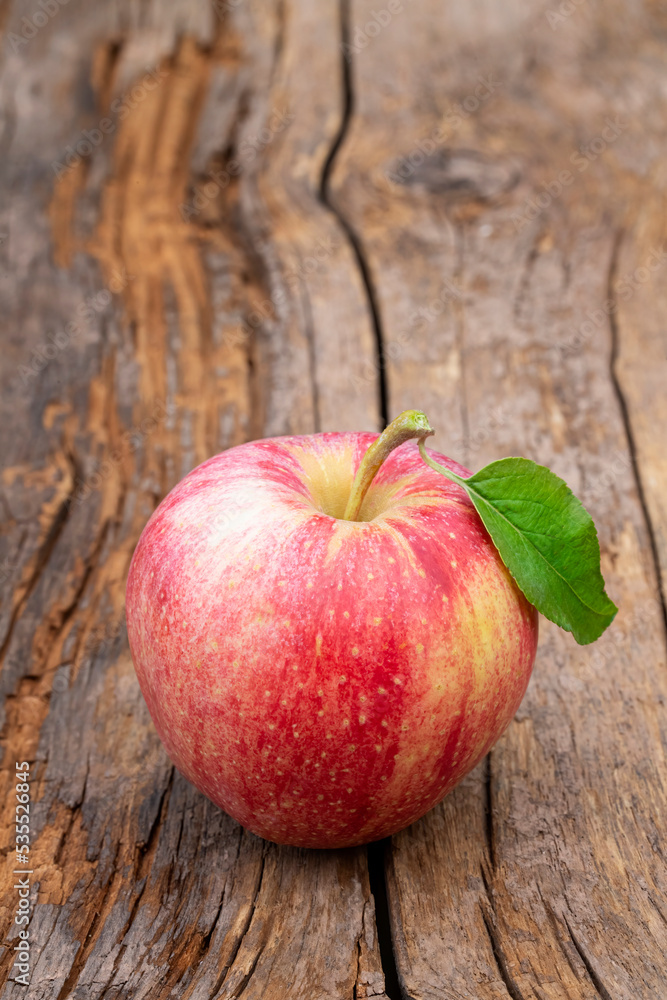 Single apple with leaf on an old farm table Single apple with leaf on an old farm table
