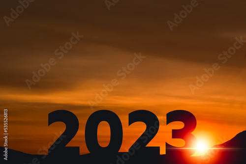 Begin 2023 year. Happy New year 2023 with large silhouette letters number on the mountain with beautiful sunset light, sunlight, golden sky and clouds for success concept. Start 2023 holiday.
