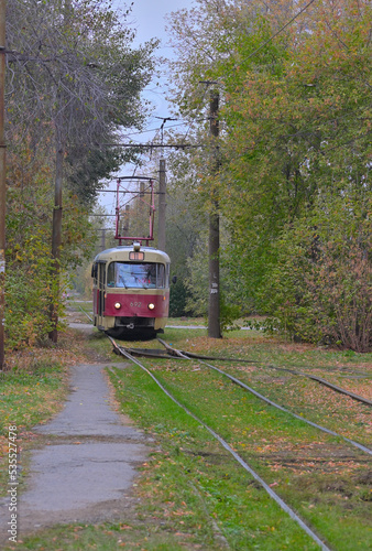 An old tram car rides on rails on an autumn day