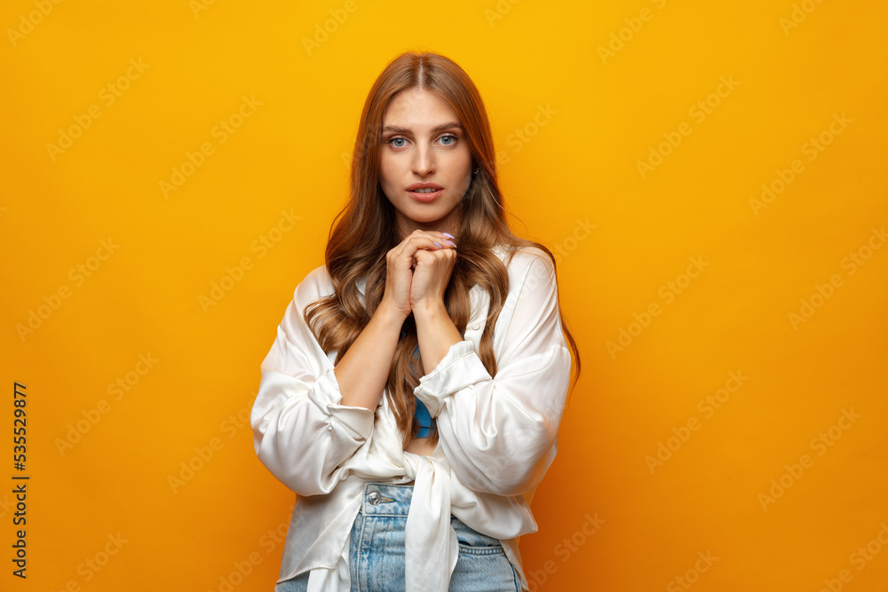 Charming blonde woman stands on yellow background looks directly at camera Charming blonde woman stands on yellow background looks directly at camera