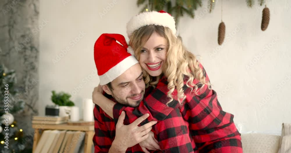 Romantic couple in santa hats hugging at home Romantic couple in santa hats hugging at home