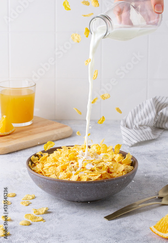 Milk is pouring into a cup with cereal, cereal is flying