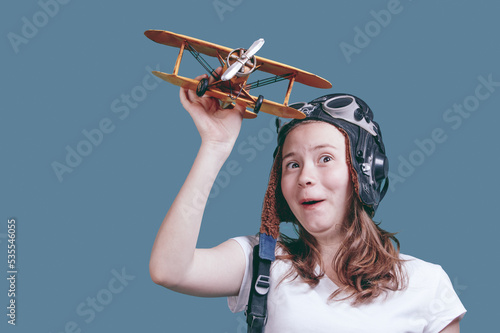 Girl with a toy plane. Young girl-pilot against the blue sky. A symbol of travel and development - a teenager dreams of flying
