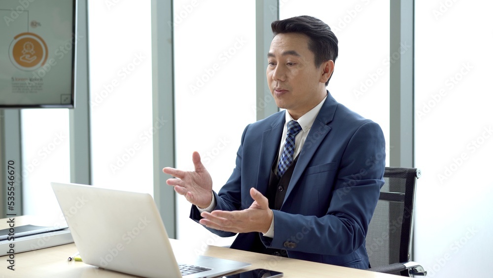 Asian senior businessman using laptop computer or notebook for online video conference in the meeting room.