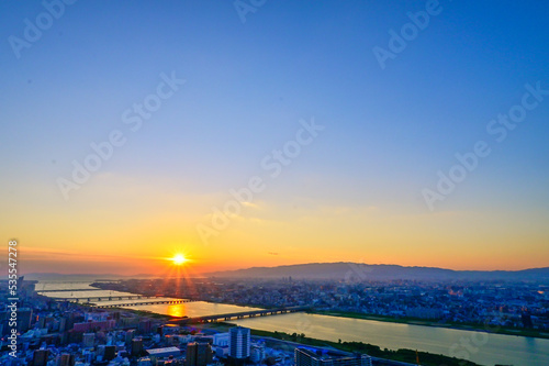 沈み行く夕陽に照らされる大阪の街並みと淀川【大阪風景】