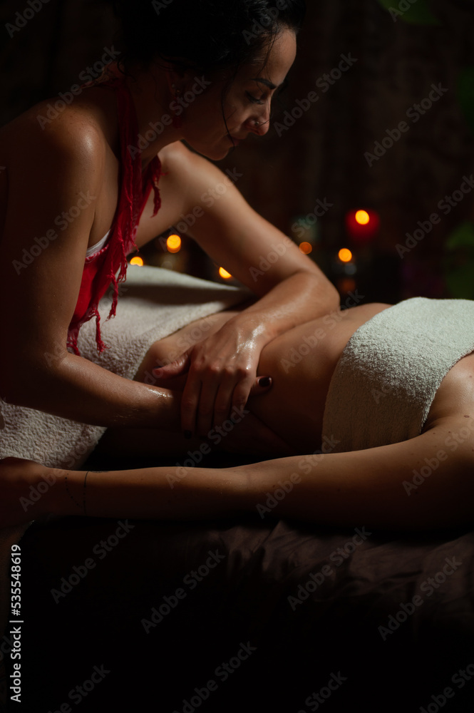 Obraz premium Professional massege woman client working at spa center. Young beautiful woman relaxing during full body massage at luxury resort wellness wellbeing pampering skin