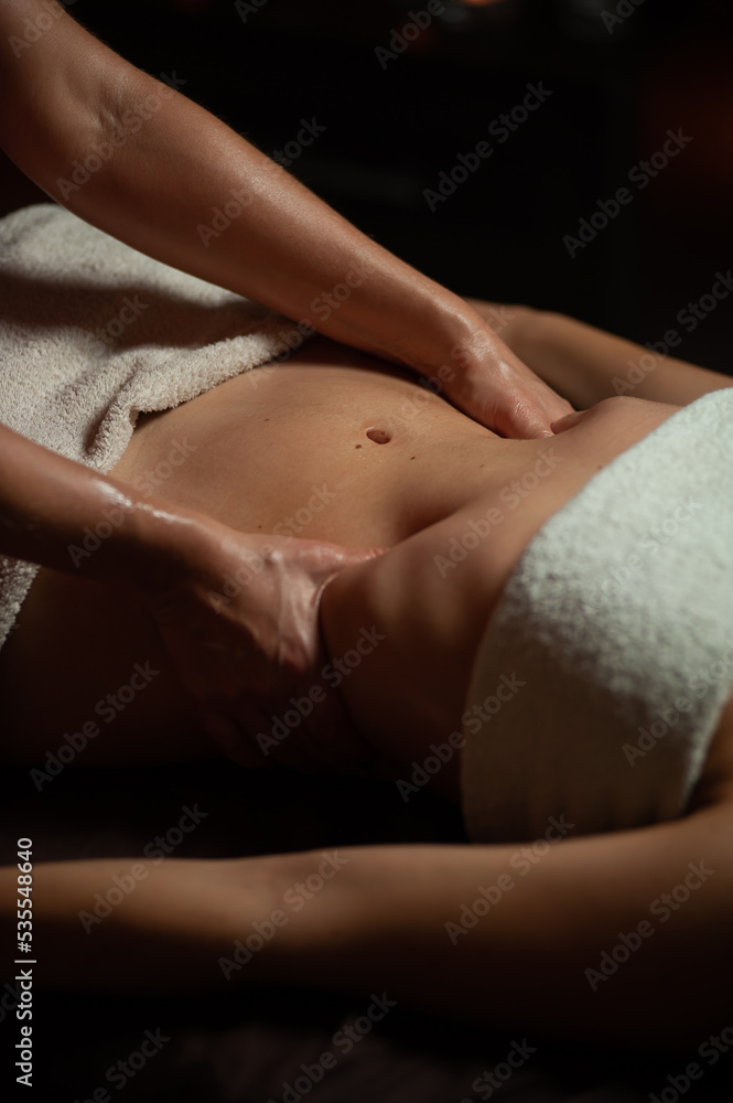 Obraz premium Girl enjoying therapeutic massage with oil in spa with dark lighting, closeup