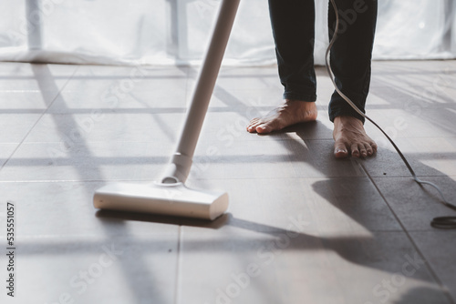 Person cleaning room, cleaning worker is using a vacuum cleaner to clean the living room floor in the company office. Cleaning staff. Maintaining cleanliness in the organization.