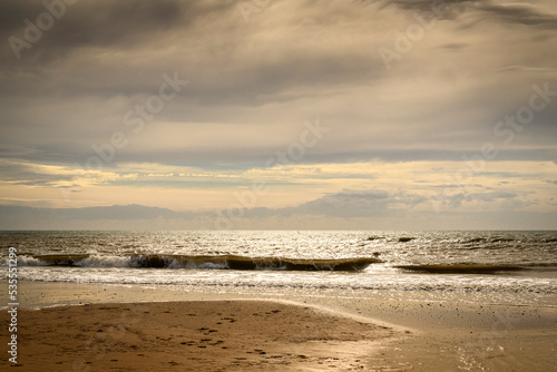 An autumnal HDR seacape image of Fleetwood beach with calm seas, hazy sun and solitude, Lancashire, England.