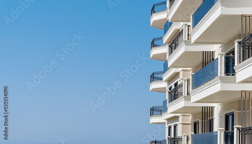 Modern apartment building with balconies isolated on sky background for ad text.