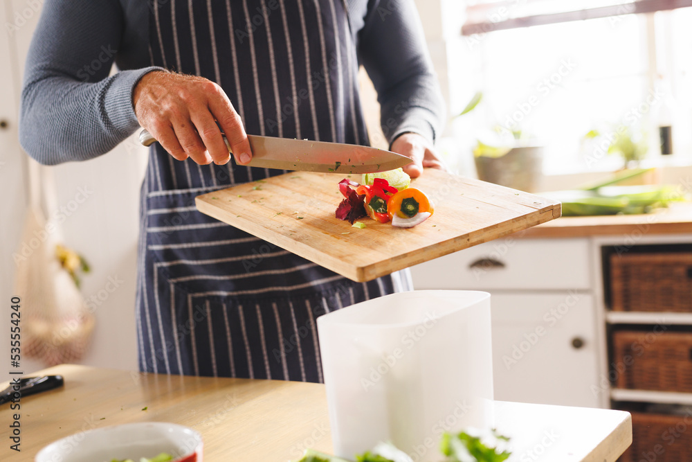 Midsection of caucasian man standing in kitchen and cooking dinner, cleaning waste Midsection of caucasian man standing in kitchen and cooking dinner, cleaning waste