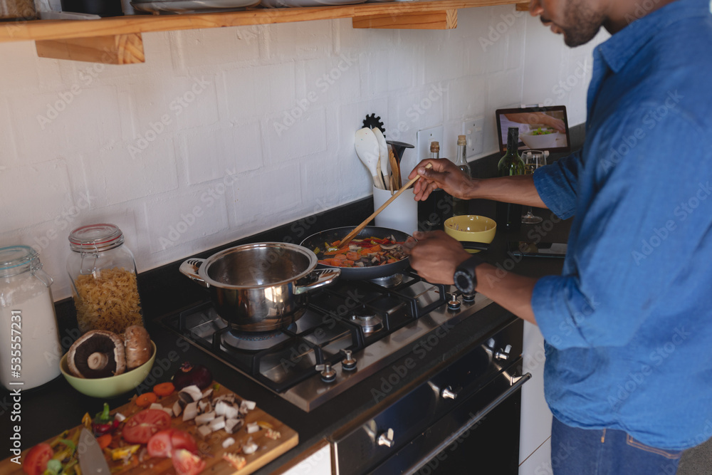 Happy african american man standing in kitchen and cooking dinner Happy african american man standing in kitchen and cooking dinner