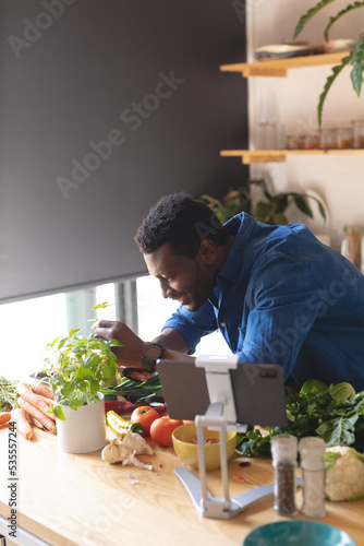 Happy african american man standing in kitchen and cooking dinner