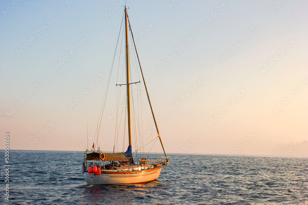 Sailing boat anchored in the middle of the sea at sunset