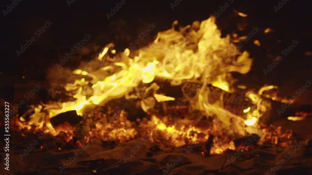 close-up of bonfire on the beach with colorful lights in the background in slow motion close-up of bonfire on the beach with colorful lights in the background in slow motion