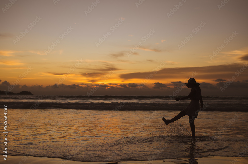 Silhouette of woman in hat on Enjoying Beautiful Sunset on the Beach
