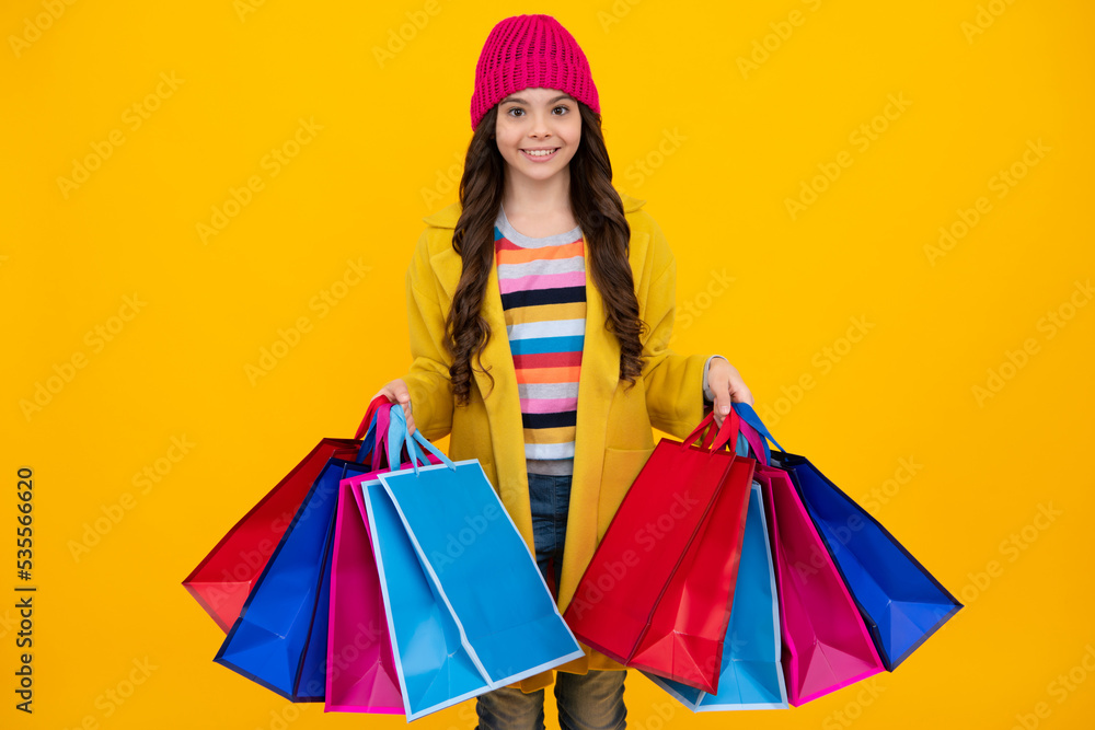 Funny teen girl hold shopping bag enjoying sale isolated on yellow. Portrait of teenager schoolgirl is ready to go shopping. Winter shopping sale.