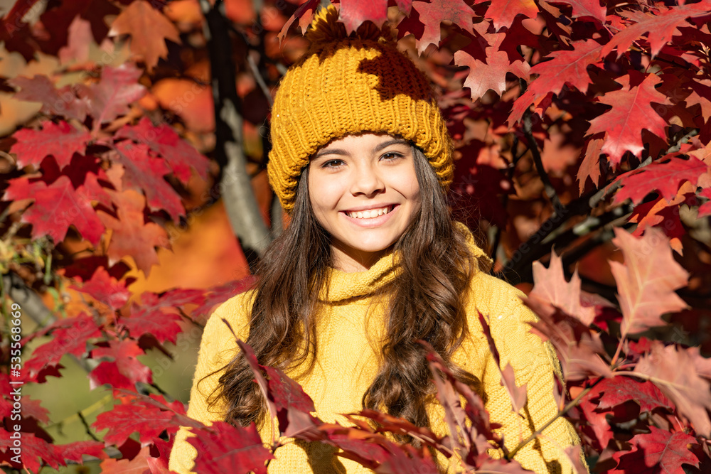 Teenager girl on autumn fall background. happy teen kid face in hat at autumn leaves on natural background Teenager girl on autumn fall background. happy teen kid face in hat at autumn leaves on natural background