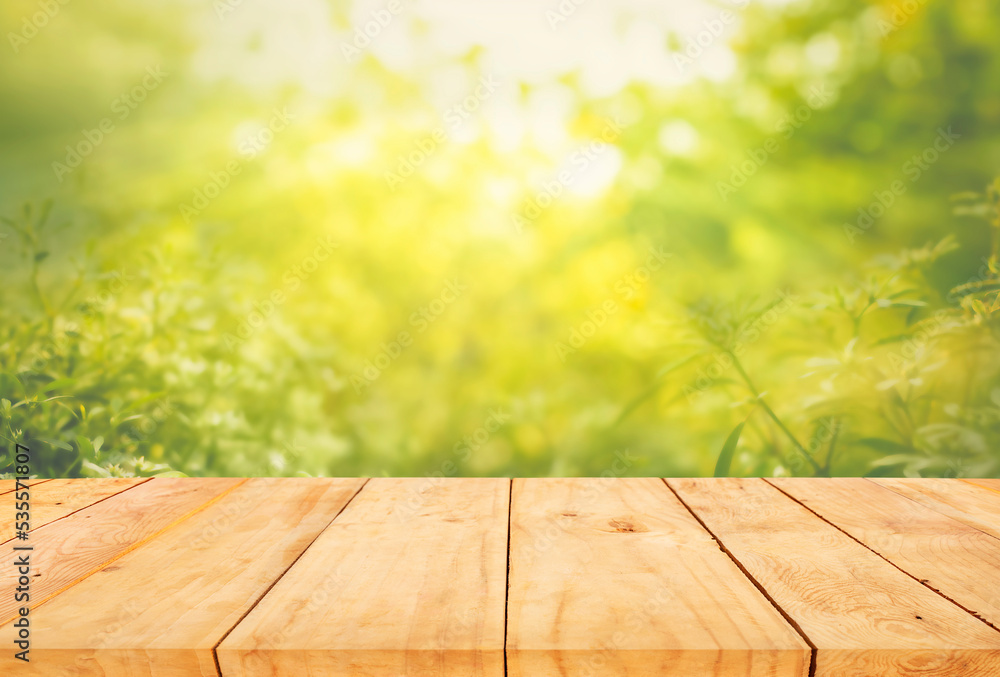 Selective focus of wood table top on blur green of tree background.