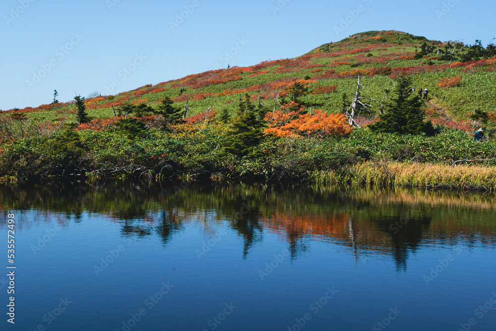 三ッ石山の紅葉　湿原の湖面の先に紅葉の頂