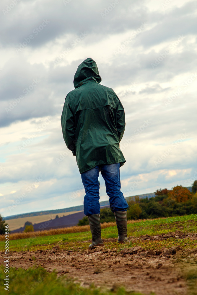A man in a field after a thunderstorm looks into the distance. The guy in the raincoat looks at the storm clouds in nature. The concept of nature, recreation, aspirations, freedom. A man in a field after a thunderstorm looks into the distance. The guy in the raincoat looks at the storm clouds in nature. The concept of nature, recreation, aspirations, freedom.