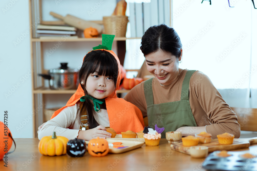 Happy halloween holiday, mother and daughter getting ready for holiday and baking cookies at home, Asian family,	