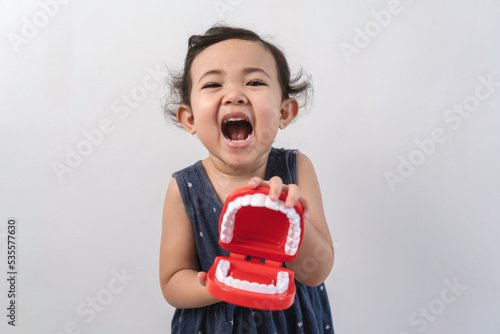 Little cute funny asian girl holding tooth jaw.Kid training oral hygiene. Child learning brushing, cleaning teeth. Prevention of caries in children. children dentistry. dental care kids