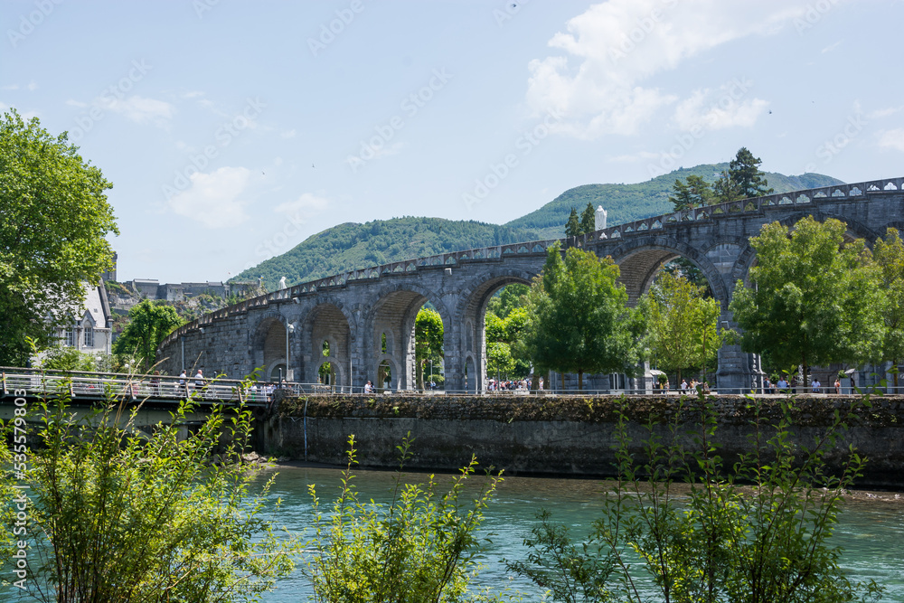 View of the river Gave de Pau and the Basilica of the Holy Rosary in Lourdes, France.