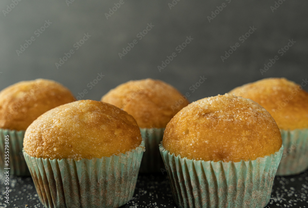 Set of delicious freshly baked cupcakes with sugar on top on a background