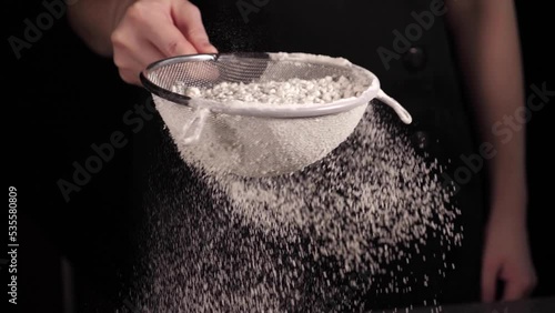 Baker sifting white wheat flour through a sieve in slow motion photo