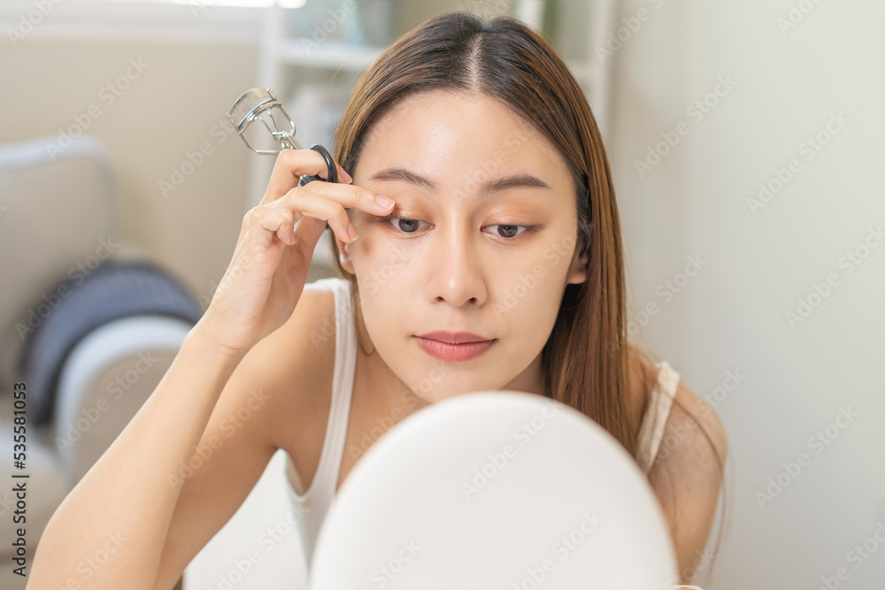 Happy beauty concept, asian young woman, girl make up face hand using eyelash curler on long eyelash before applying mascara brush, looking mirror in morning routine. People look with natural fashion. Happy beauty concept, asian young woman, girl make up face hand using eyelash curler on long eyelash before applying mascara brush, looking mirror in morning routine. People look with natural fashion.