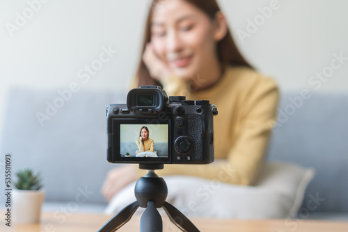 Vlogger influencer, attractive asian young woman blogger, content maker looking at camera, recording interview sit on sofa, talk on video shooting social media, live broadcast with technology at home.