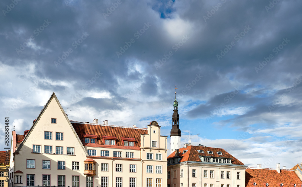 Obraz premium Tallinn old houses and Town Hall tower from Vanaturu kael, Old Town, Tallinn. Heavy rain clouds, dramatic sky before rain. Tallinn is in Harju County, Republic of Estonia